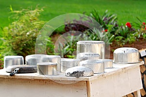 Washed saucepans drying on a table outside a cottage