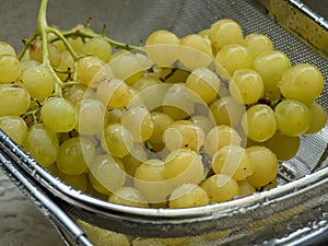 Washed yellow table grapes in a strainer closeup