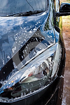 Washing black car with foam and soap