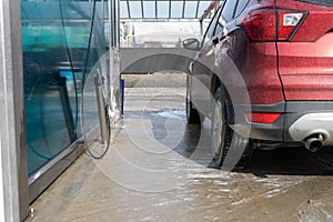 Washing car at autowash . Car wash. red machine under the pressure of water at a car wash. Red car in foam