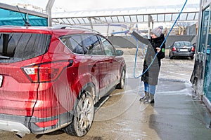 Washing car at autowash . Car wash. red machine under the pressure of water at a car wash. Red car in foam