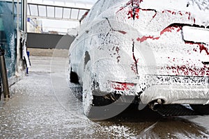 Washing car at autowash . Car wash. red machine under the pressure of water at a car wash. Red car in foam