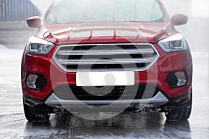 Washing car at autowash . Car wash. red machine under the pressure of water at a car wash. Red car in foam