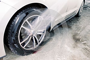 Washing a car in detailing service. Close up image of the process of washing the car wheels rims with a high pressure