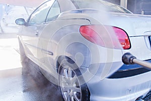 Washing car with pressure washer at self-service
