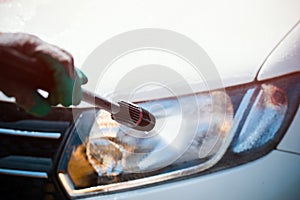 Washing a car`s lamp with pressurized water