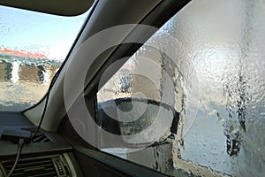 Washing car in a self-service car wash station. Shooting from inside the car