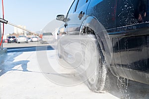 Washing car wheel by water pressure at self-service station