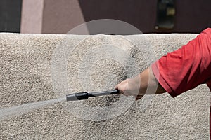 Washing carpets with high pressure washer. Cleaning the carpet with a gun for washing high pressure water