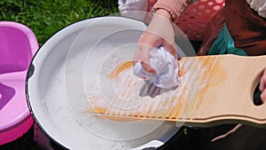 Washing clothes on old vintage washboard outdoors. Young Woman washing on old retro washboard. Close up shot footage