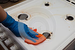 Washing a dirty kitchen stove by a man in gloves