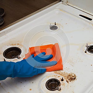 Washing a dirty white kitchen stove by a man in gloves