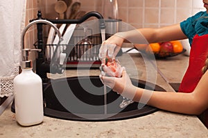 Washing the dishes - child hands cleaning a glass with sponge, s