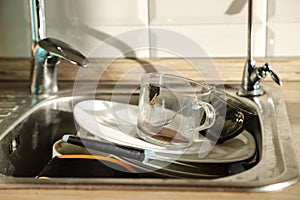 Washing dishes by hand. Pile of dirty dishes in stainless steel kitchen sink