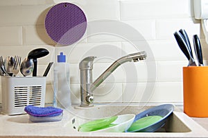 Washing dishes in the kitchen. Dirty dishes plates and glasses lie in the sink. front view. homework