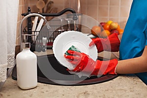 Washing the dishes after a meal - child hands scrubbing a plate photo