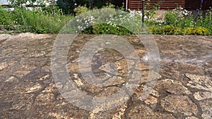 Washing the driveway under pressure, a man's hand under pressure sprays an aqueous solution on the sidewalk near the