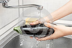 Washing eggplant under a stream of water