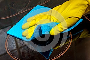 washing the electric stove with a glass-ceramic surface - a gloved hand with a rag