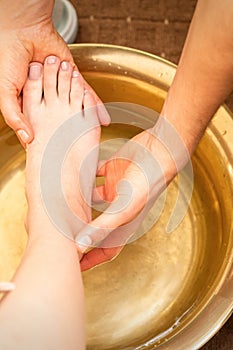 Washing female foot in a special container by male masseur in spa salon.