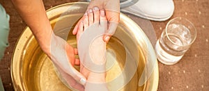 Washing female foot in a special container by male masseur in spa salon.