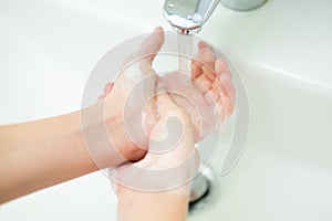 Washing of female hands with soap in bathroom