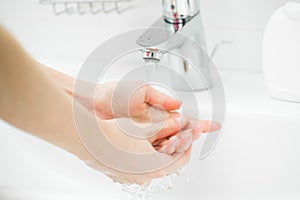 Washing of female hands with soap in bathroom