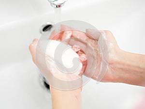 Washing of female hands with soap in bathroom