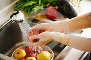 Washing fruit in the kitchen, white hands