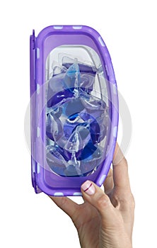 Washing gel capsules for delicate machine wash in purple plastic box in the hands of a woman isolated on a white