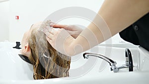 Washing hair and head massage in beauty salon before female haircut. Hairstylist washing hair with shampoo in