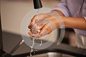 Washing hands, sink and water cleaning for wellness, health and hygiene hand care in a home. Person at a house kitchen