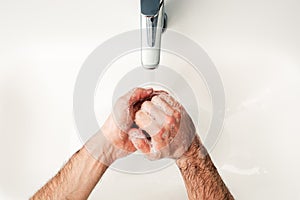 An washing hands with soap in the bathroom