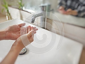 Washing hands with soap in the bathroom sink at home to prevent viruses and bacterias.