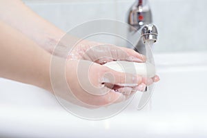 Washing hands with soap and stream of water in bathroom for health care. photo