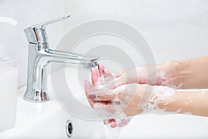 Washing hands with soap under the faucet with water