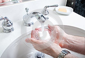 Washing hands with soap in washroom sink