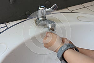 Washing hands under flowing tap water.