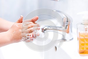 Washing hands with water and liquid soap in the bathroom.