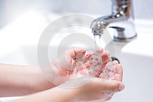 Washing hands with water and liquid soap in the bathroom.