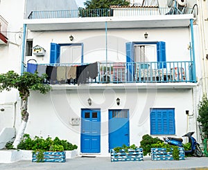 Washing hanging from balcony of typical blue doors and shutters against whitewashed walls of Greek island architecture