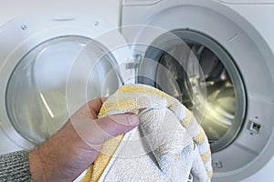 washing light-colored clothes in the washing machine. man holding a towel
