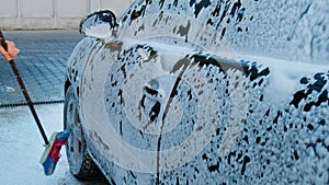 Washing luxury black car on touchless car wash. Cleaning the details of car. Washing sedan car with foam self-service