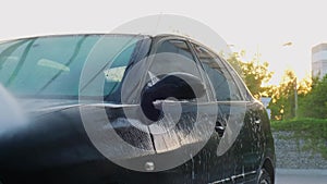 Washing luxury black car on touchless car wash. Cleaning the details of car. Washing sedan car with foam self-service