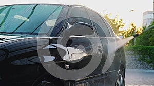 Washing luxury black car on touchless car wash. Cleaning the details of car. Washing sedan car with foam self-service