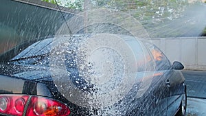 Washing luxury black car on touchless car wash. Cleaning the details of car. Washing sedan car with foam self-service