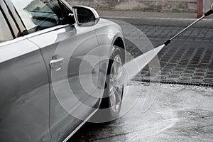 Washing luxury silver car on touchless car wash. Washing sedan car with foam self-service and high pressure water