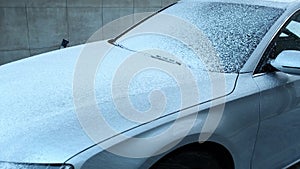 Washing luxury silver car on touchless car wash. Washing sedan car with foam self-service and high pressure water