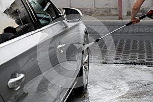 Washing luxury silver car on touchless car wash. Washing sedan car with foam self-service and high pressure water