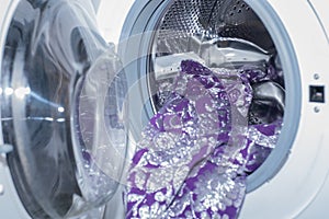 Washing machine with bright clothes, close-up. Washday. Washing festive bright clothes in the washing machine. Soft focus. photo